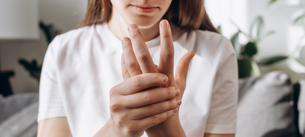 woman with finger and hand pain, rubbing her hand