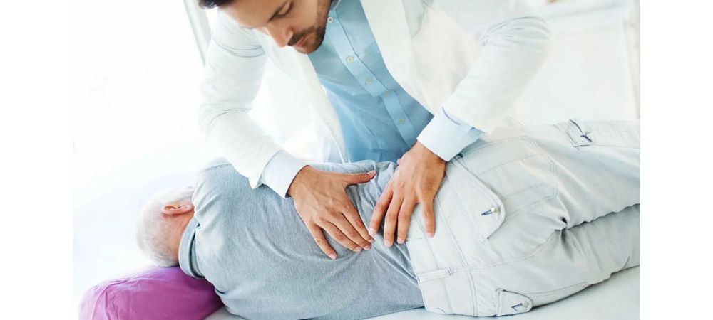 doctor assessing elder patient's lower back