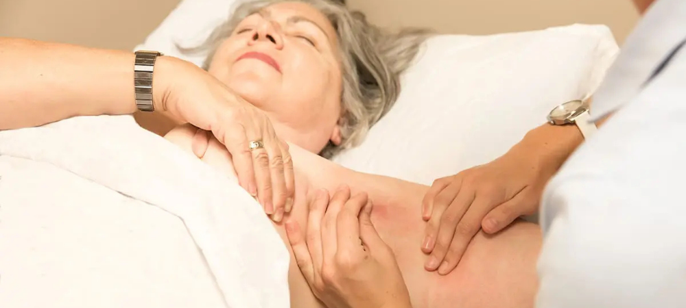 doctor palpating lymph nodes in woman's armpit