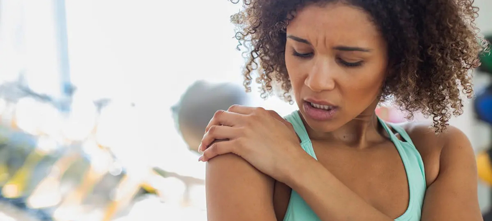 woman with shoulder pain rubbing shoulder