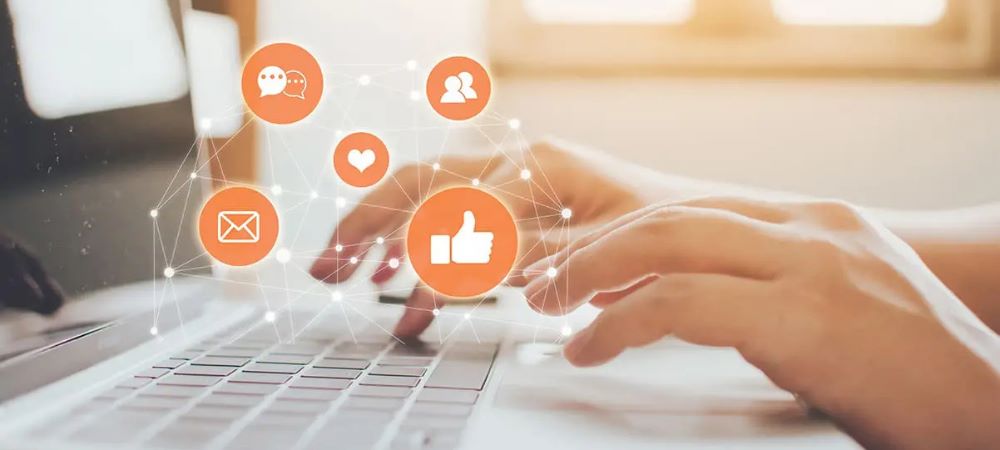 hands typing on a keyboard with social icons flying above them