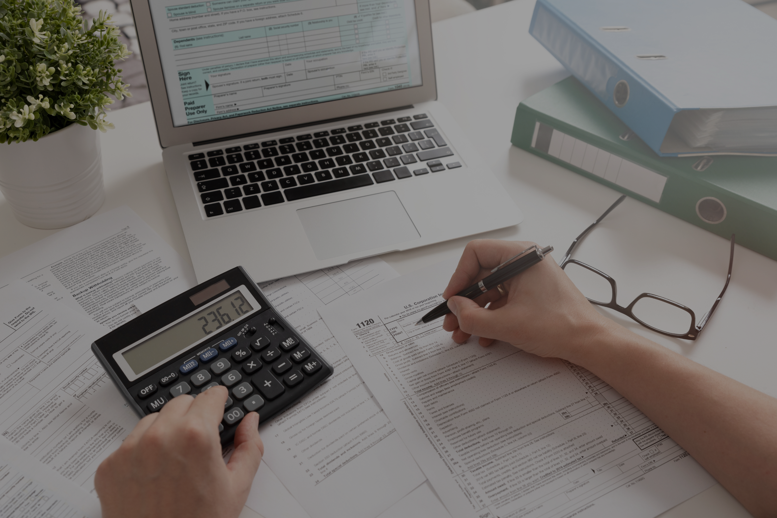 person with a calculator and laptop working 